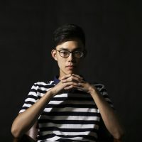 一位戴眼镜的男性编辑坐在办公桌前整理实测笔记，身后书架上摆满资料册，室内暖色台灯光线